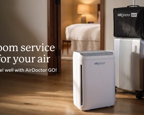 AirDoctor GO portable air purifier beside luggage in a hotel room, with the text Room service for your air