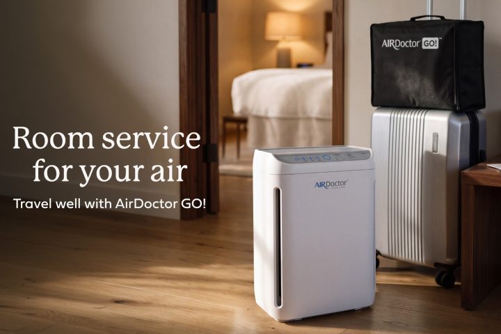 AirDoctor GO portable air purifier beside luggage in a hotel room, with the text Room service for your air